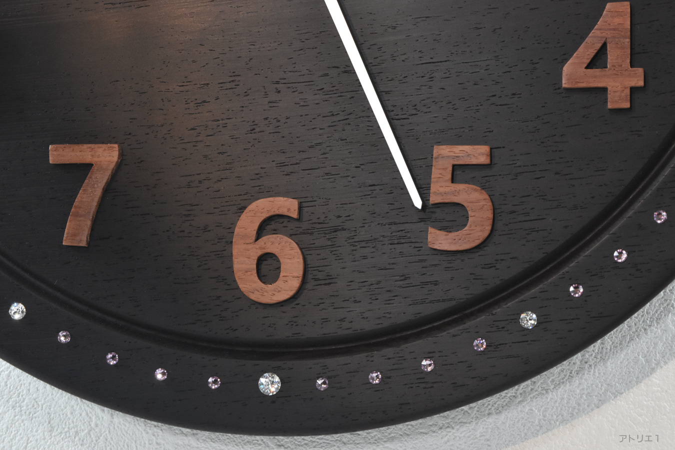 ウエンジの黒い色合いに合うよう秒・分目盛りには、ライトアメジスト色を使用し、時刻目盛りには、わかりやすいようにクリスタルを用い、12時、3時、6時、9時にはアクセントとして大きめのクリスタルを使用しています。