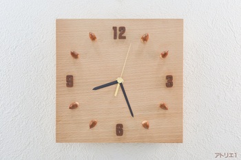 時刻目盛りの12時、3時、6時、9時はブナとは対照的な濃い色のマホガニーを数字に切り出し、その他の時刻はどんぐりを配しました。どんぐりは虫食いなどに合わないように中身を掘り抜き、樹脂系接着剤を埋め込んで加工しました。また、ブナの美しい色あいやどんぐりの印象を損なわないよう、蜜蝋クリームを塗って仕上げています。