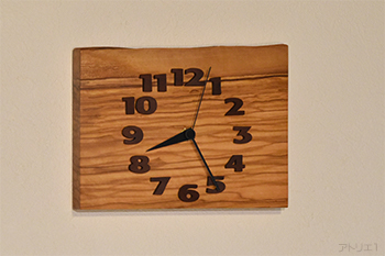 オリーブの耳付きの一枚板で作った掛け時計です。オリーブならではの印象的なマーブル模様の木目を楽しめるように余計な加工はせず、四角く切り出して時計にしました。