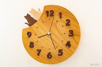 けやきは日本を代表する樹木で強靭で狂いが少なく耐朽性にも優れているという実用性の高い特徴を持ち、古来より日本国内で最良の広葉樹として扱われてきました。そんなけやきを少し欠けた月の形に切り出し、そこに仲良く並んで座る黒猫と白猫を配した掛け時計にしました。