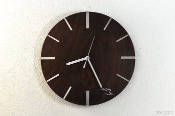 新居のリビングの掛け時計に飾るシンプルモダンな木婚式の記念の掛け時計です。ブラックウォルナットの中でも装飾的な価値の高い木目の材をご希望のサイズの時計にしました。木目を堪能していただくために、表面はフラットで蜜蝋クリーム仕上げのシンプルな仕上げにしました。