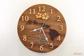 時計の真ん中ににハワイ諸島とハイビスカスの花とホヌを配したハワイの掛け時計です。時計のベースは、CMにある「この木なんの木、気になる木･･･」というテーマソングで映し出されるハワイ州のオワフ島にある「モアナルア・ガーデンパーク」にある木と同じモンキーポットです。