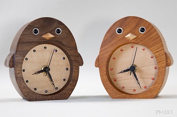 水族館でも人気者のペンギンをモチーフに無垢の木の時計です。お互いの時間を一目で確認できる2台セットの置き時計です。それぞれの時間がわかるようにブラックウオルナットとけやきの2種の木で制作しました。
