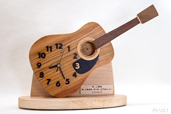 ギターの形を60度時計方向に回転させて時計にした置き時計です。古くは浮世絵の版木に使われ、近代では、楽器や食器、定規などの道具にも使われ、高級家具等によく用いらる無垢の「山桜」でボディを制作しました。