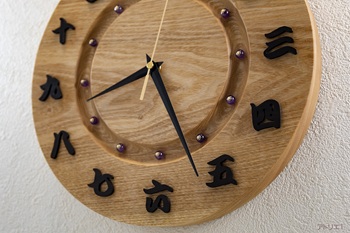 時刻の漢数字には、黒檀からひとつずつ切り出したものを使い、墨でしっかりと書き出されたように視認性をよくしました。時刻目盛りは紫水晶（むらさきすいしょう）ともいわれてる紫色のアメジストを使用しています。真鍮色の座金で止めて、和の高貴なイメージを感じるようにしました。
