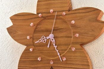 時刻目盛りの内側を丸く一段彫り込んで木目の変化を楽しむデザインにしました。時刻目盛りは桜の花びらの形のガラスピンにし、針はアラベスクデザインでピンクにしました。