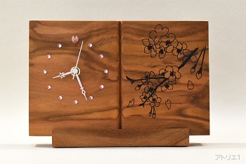 書見台に本が乗っているかのようなデザインの桜の置き時計です。置き台に時計の板厚分の溝を掘り、そこに嵌める形で置き時計にします。