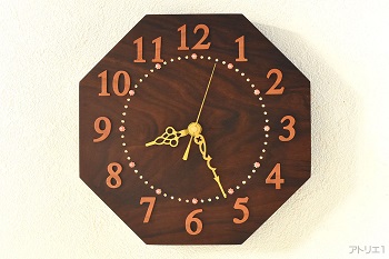 超高級木材のローズウッドを八角に切り出し、ピンクのサンゴと金色の目盛りとピンクアイボリーの数字がおしゃれな気品のあるデザインの掛け時計です。