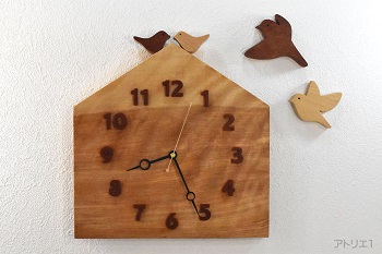 杢のある美しいカバザクラの木をおうちの形に切り出した掛け時計です。おうちの屋根に小鳥が乗っている幸せな形にした可愛い時計に仕上げました。小鳥を羽ばかせたデザインのウォールデコも時計本体の小鳥と同じ木で制作しました。