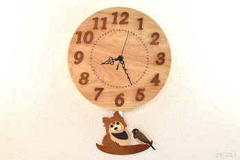 天然檜の丸い時計にポメラニアンと桜文鳥が乗ったかごの振り子が付いた掛け時計です。