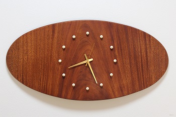 マホガニーの大樹の木目を堪能できる大型の掛け時計です。板が反っていることを利用した楕円のデザインに大きな文字盤を配した掛け時計なので、大きな空間でも時間の視認性が高くなっています。