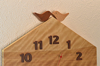 2羽の小鳥が仲良く向かい合って屋根の上にいるデザインです。時刻の数字はカリンの木をひとつずつ糸鋸で切り出しました。