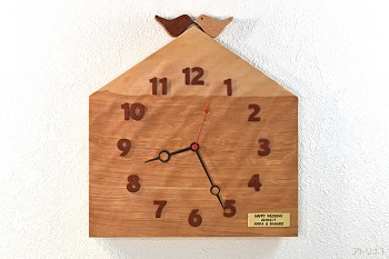 杢のある美しいカバザクラの木をおうちの形に切り出した掛け時計です。おうちの屋根に小鳥が乗っているシンプルながら可愛い時計に仕上げました。