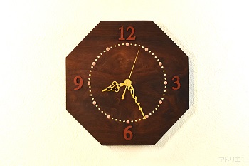 超高級木材のローズウッドを八角に切り出し、ピンクのサンゴと金色の目盛りとピンクアイボリーの数字がおしゃれな気品のあるデザインの掛け時計です。