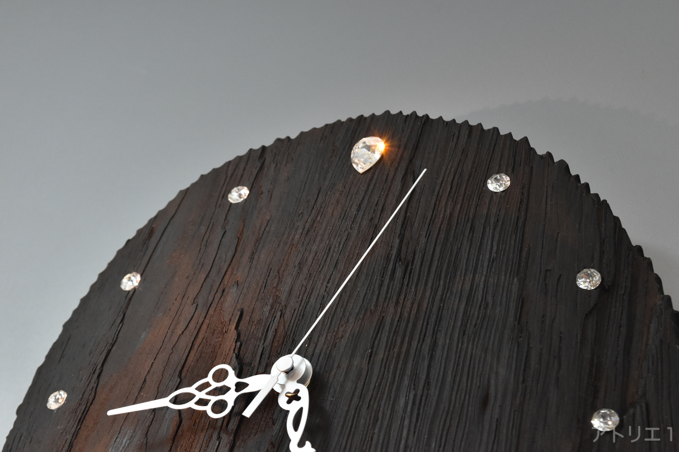 目盛りは、スワロフスキーのクリスタルを使用し、ウェンジ固有のダークカカオ色の非常に硬い漆黒の木肌はスワロフスキーのクリスタルの輝きが似合います。そして、どこから見てもその輝きが際立ちます。12時の部分にはトロップカットのクリスタルを使用しました。針もシルバーとし、デザインと視認性を両立させました。