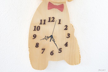 時刻の数字には、美しい深い紫色のチンチャンの無垢板を斜体のかかった明朝体調の数字に切り出して時刻を見やすくしています。針はアラベスクデザインの黒い針にしてあります。また、顎の下には、「木のダイヤモンド」と称され高級な装飾や、小物などに使われているピンクアイボリーから切り出したリボンをアイキャッチとして配してあります。