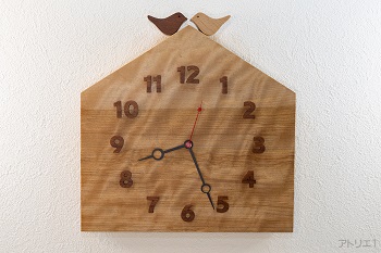 杢のある美しいカバザクラの木をおうちの形に切り出した掛け時計です。おうちの屋根に小鳥が乗っている幸せな形にデザインした可愛い時計に仕上げました。