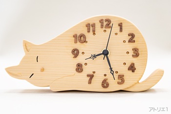 時計本体は、無垢の天然檜で制作しました。檜は福島県以南から九州にかけて生育し、寺社建築をはじめ高級建築材として使われるほか、耐湿・耐水性が良くお風呂などにも利用されてきた日本人としてなじみの深い木です。時刻の数字は高級家具や、彫刻の材料として主に使用され、木造の帆船の建造や船室の内装などにも利用されてきたマホガニーから見やすい字体をひとつずつ切り出しましたので、立体的な陰影で視認性が大変よくなっています。更にその内側にスモークトパーズ色のスワロフスキーの時刻目盛りを配しています。鼻は、ヨーロッパ全体に分布していて、主に装飾部分の材料、家具、リコーダーやバイオリンなどの楽器などの材料として用いられるペアウッドです。無垢材ならではの本物の質感と温かみがあります。